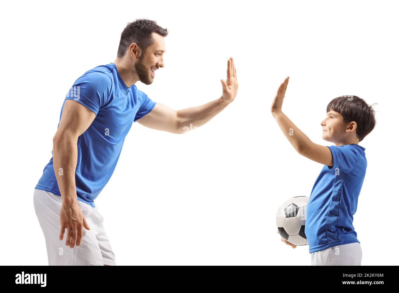 Jugador de fútbol haciendo gestos de cinco altos con un niño aislado sobre fondo blanco Foto de stock