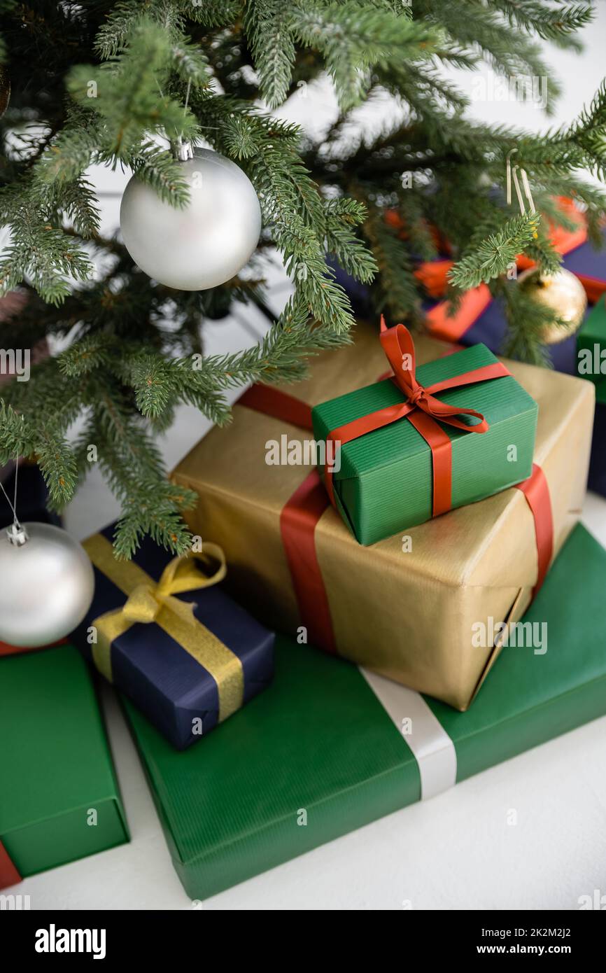 vista de alto ángulo de coloridas cajas de regalo con cintas y arcos cerca del árbol de navidad decorado, imagen de archivo Foto de stock