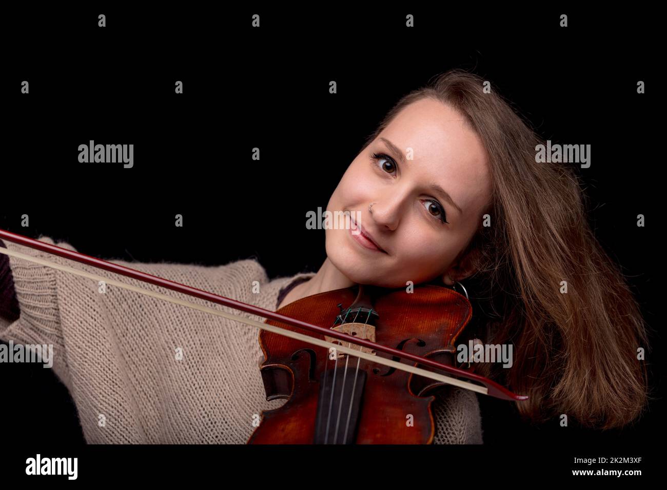 mujer sonriente tocando violín sobre fondo negro Foto de stock