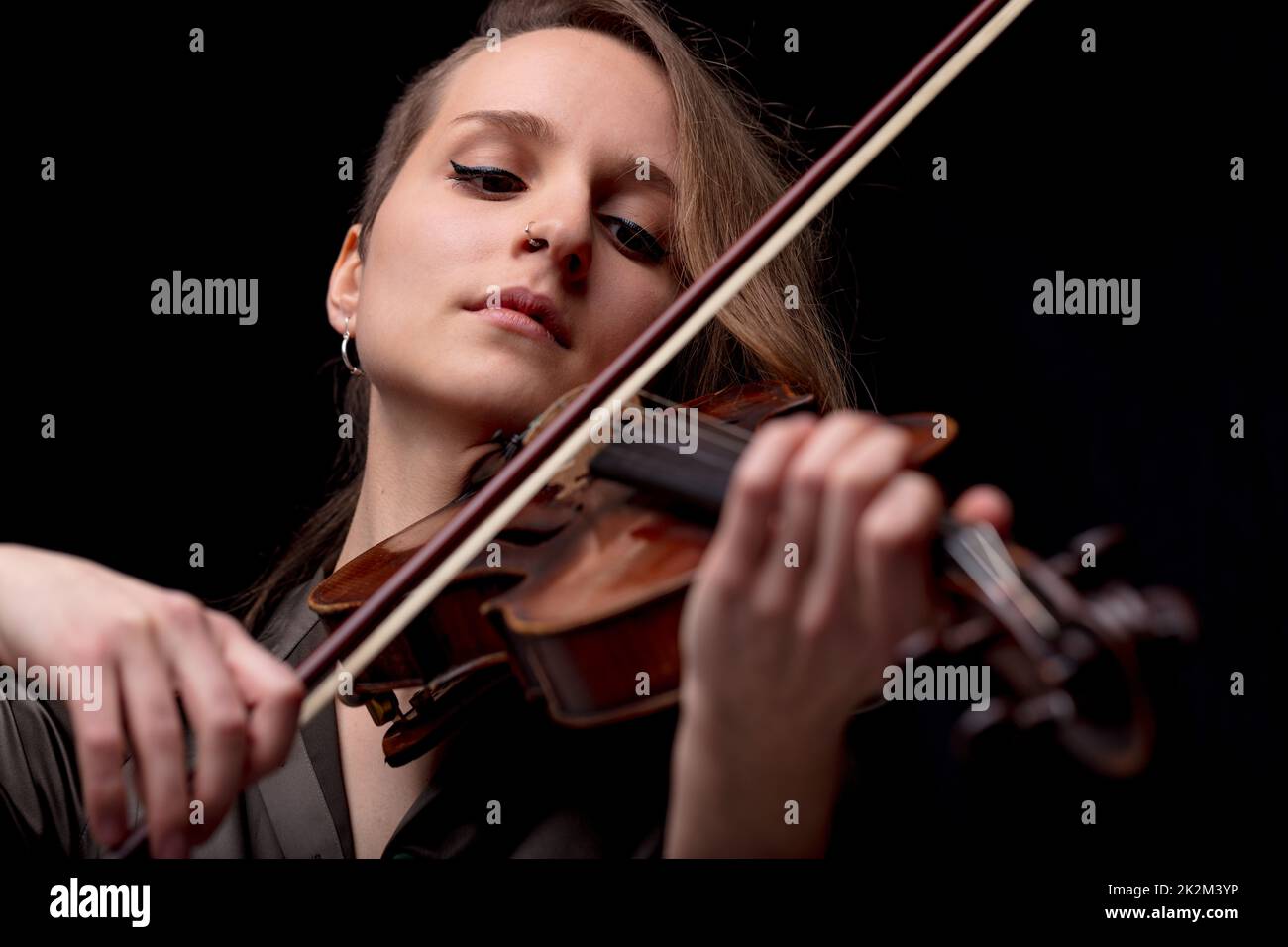 seria bonita mujer tocando violín sobre negro Foto de stock