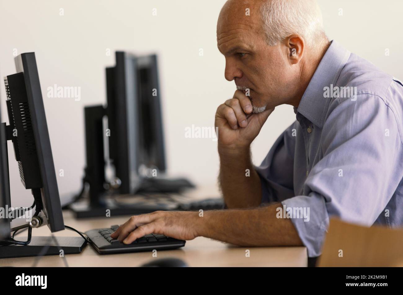 Vista de perfil de un anciano que trabaja en el ordenador. Foto de stock
