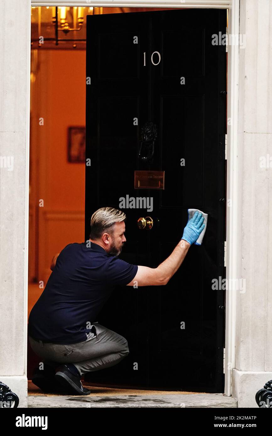 Una persona limpia la puerta principal del 10 Downing Street, Londres. Fecha de la foto: Viernes 23 de septiembre de 2022. Foto de stock
