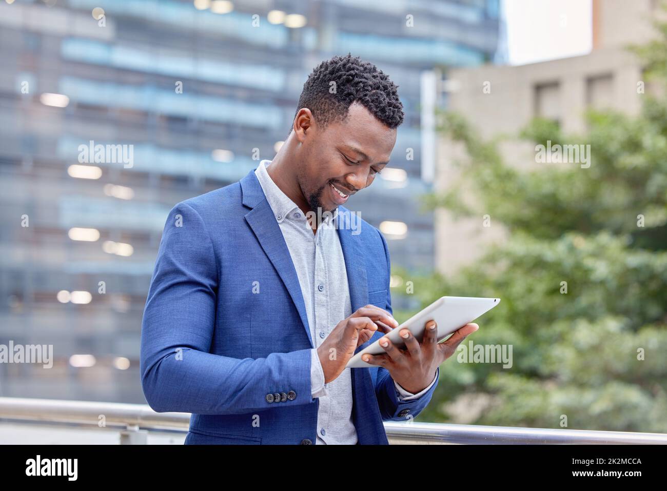 Hes tiene todas las conexiones. Foto de un joven hombre de negocios usando una tableta digital contra un fondo de la ciudad. Foto de stock