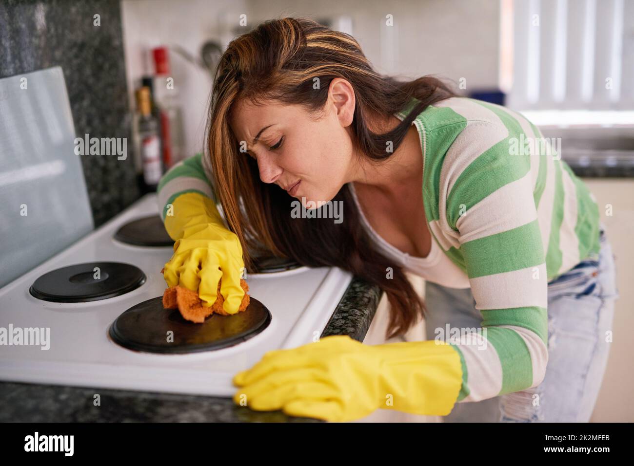 Esta queja simplemente no se apagará. Foto de una mujer joven limpiando una estufa de cocina. Foto de stock