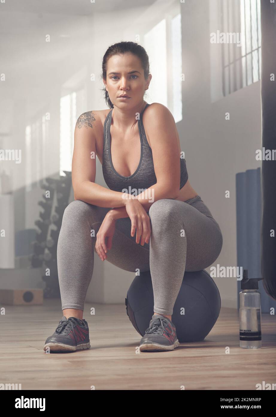 .. Tiro de una joven atleta sentada en una pelota de ejercicio en el gimnasio. Foto de stock