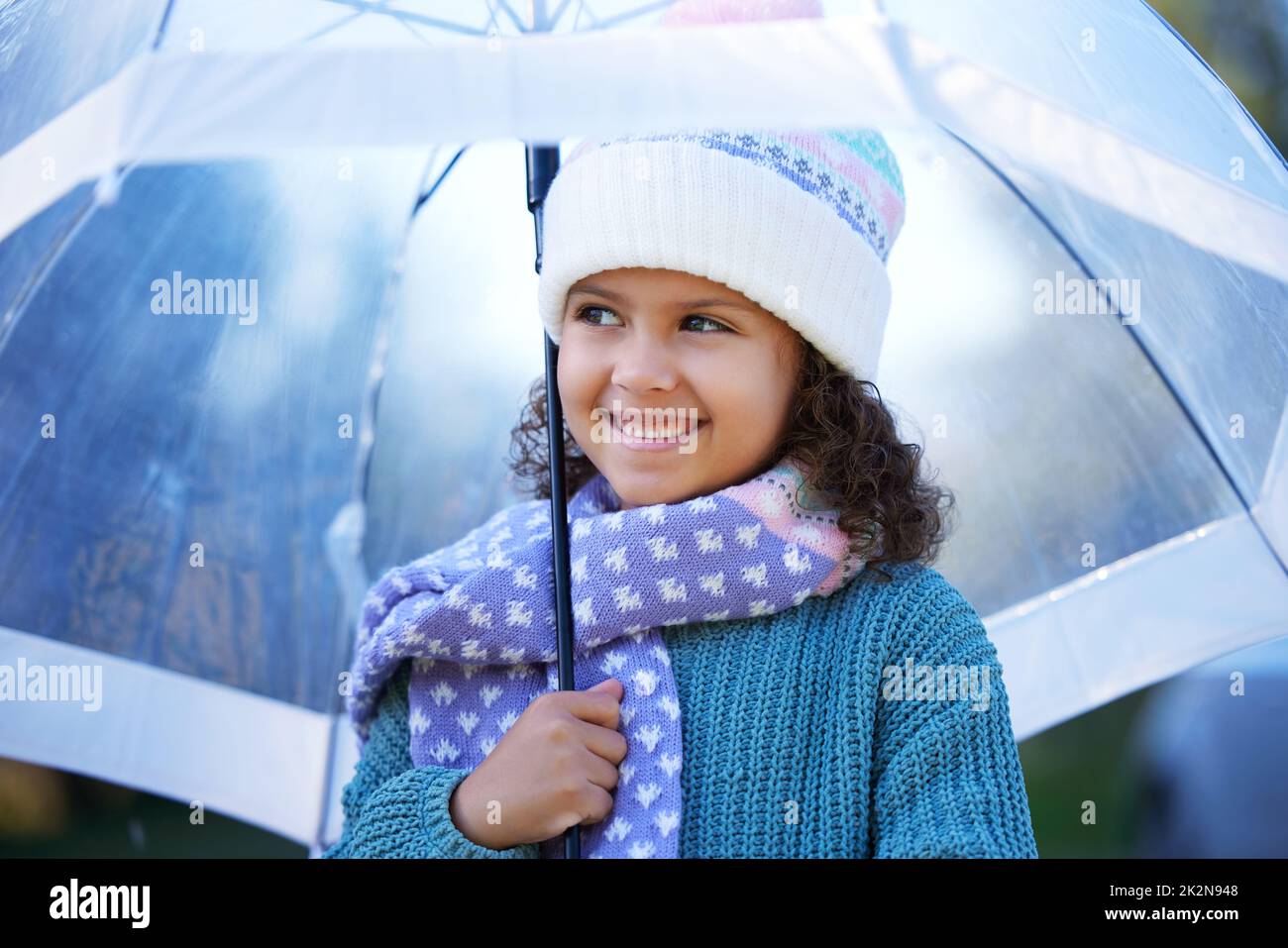 La lluvia siempre ha sido mi favorita. Tiro de una adorable niña de pie fuera y sosteniendo un paraguas. Foto de stock