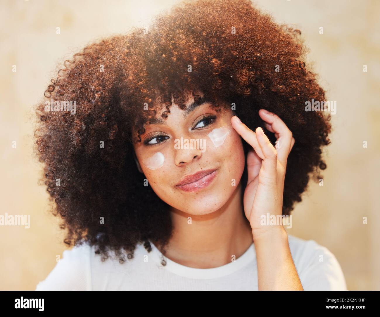 ¿Su crema hidratante le deja sentirse bien en el interior y el exterior. Foto de una hermosa mujer joven aplicando humectante a su cara. Foto de stock