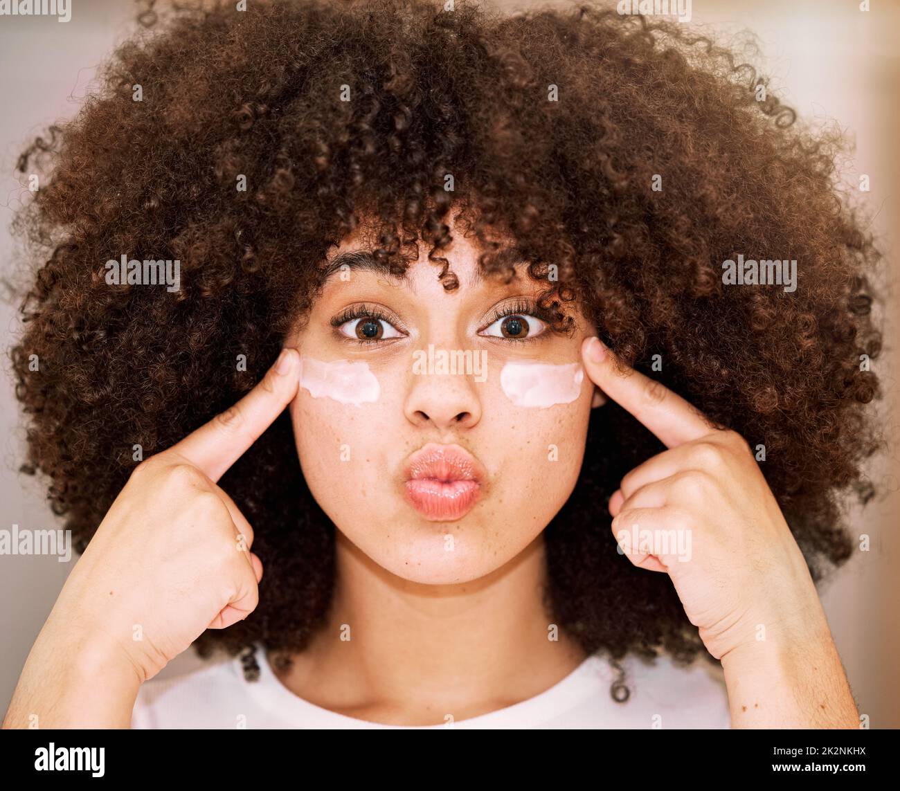 Mira brillar. Foto de una hermosa mujer joven aplicando humectante a su cara. Foto de stock