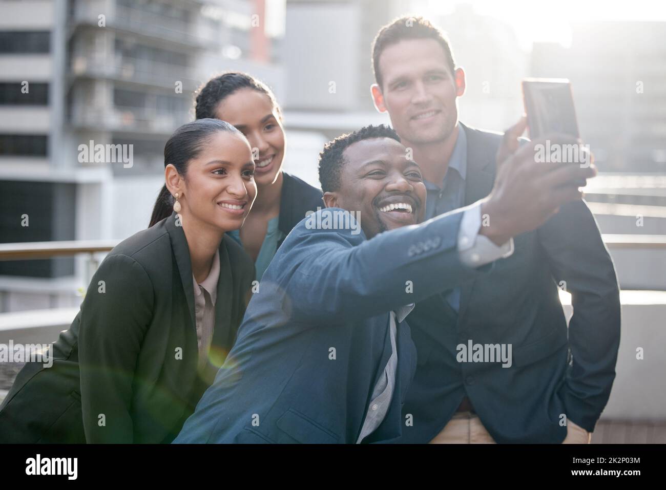 Conseguir que el espíritu de equipo vaya. Foto de un grupo de empresarios tomando un selfie contra un fondo de la ciudad. Foto de stock