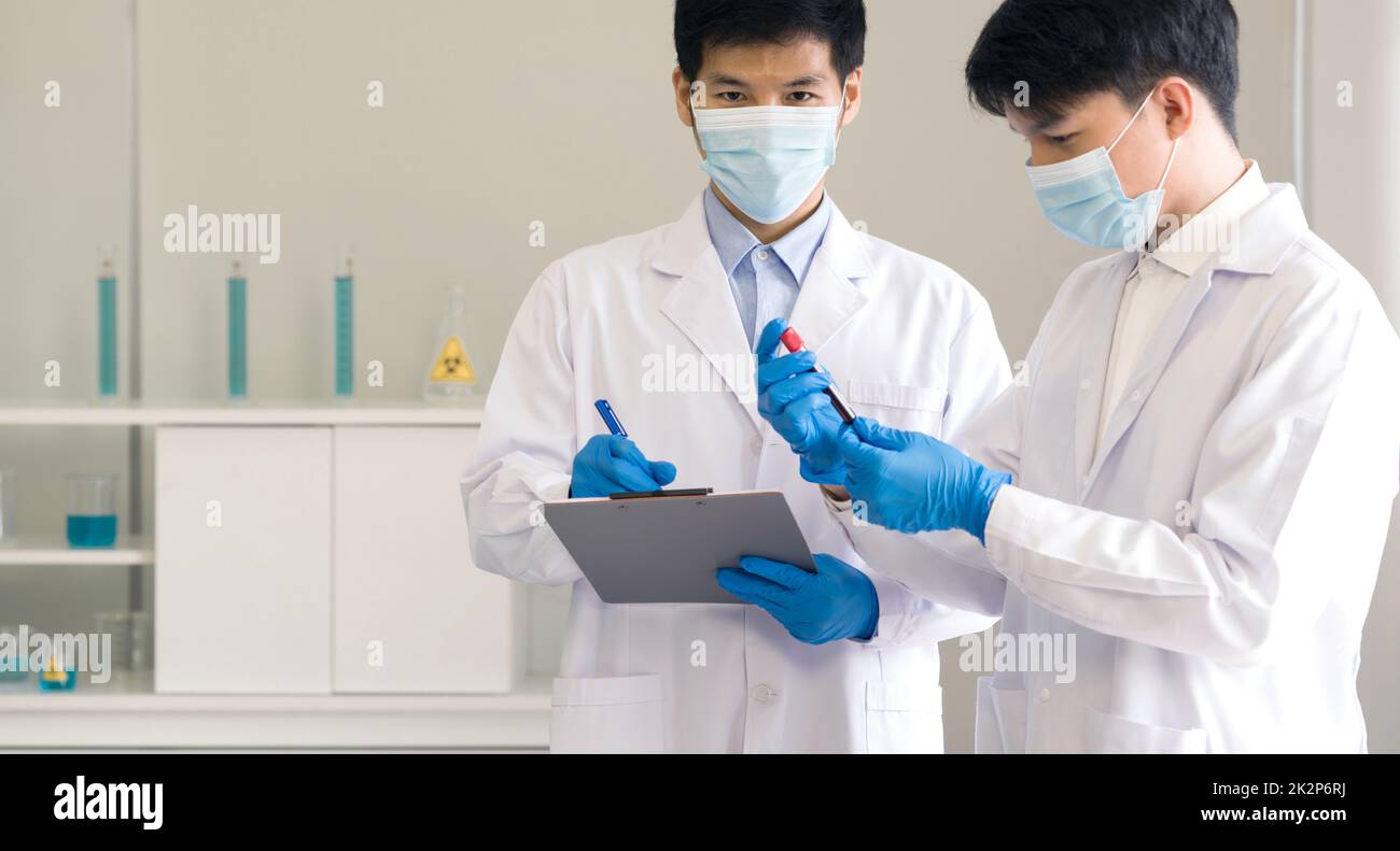 Pruebas COVID-19 en laboratorio. Dos científicos discuten sobre muestras de sangre de pacientes infectados con la enfermedad de Coronavirus 2019. Concepto médico y sanitario. Foto de stock