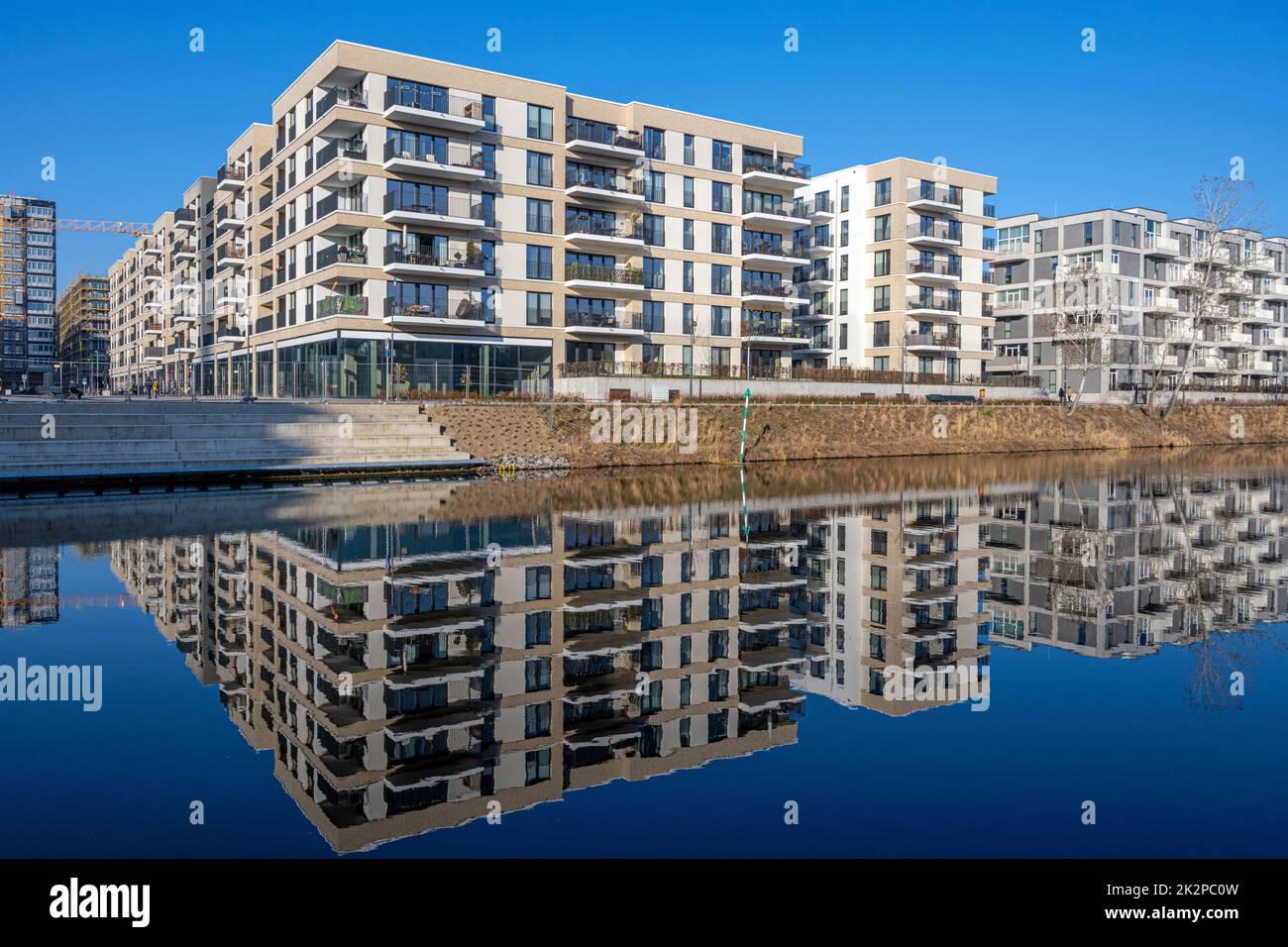 Modernos edificios de apartamentos en Berlín con una perfecta reflexión en un pequeño canal Foto de stock