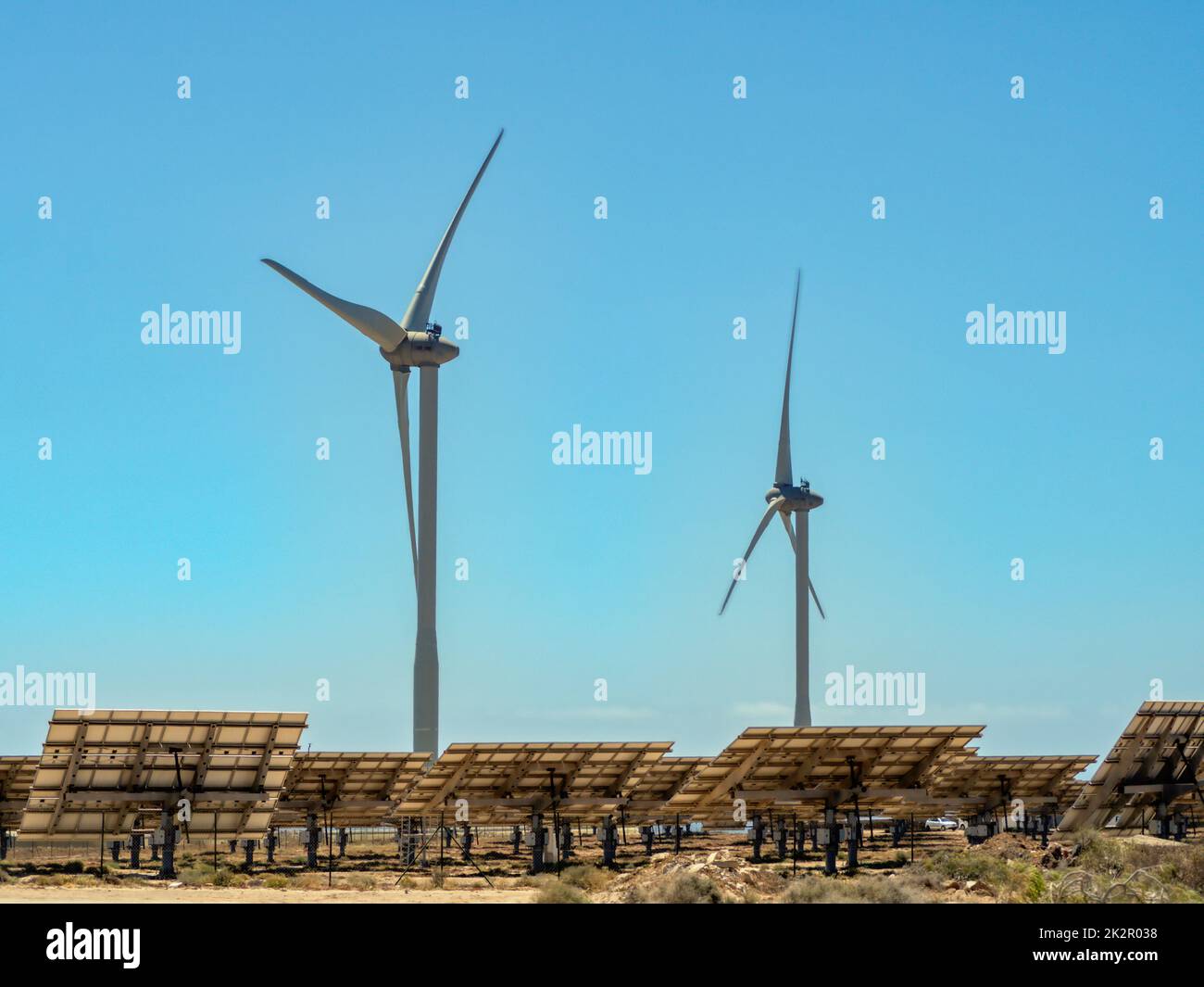 Energía ecológica procedente de turbinas solares y eólicas, aquí dos turbinas eólicas y varios campos solares Foto de stock