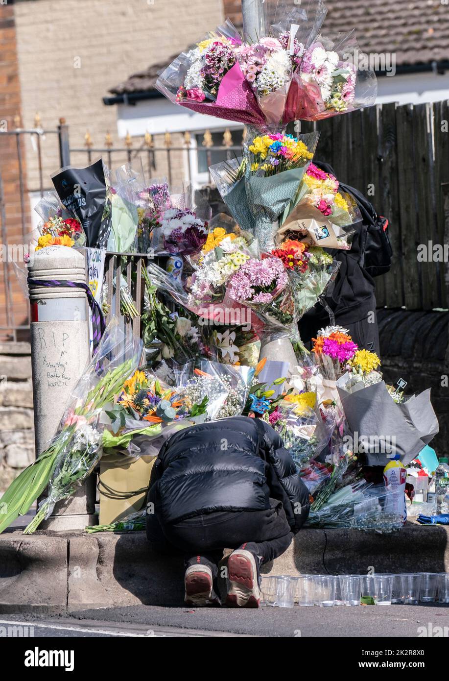Un alumno se agachó junto a homenajes florales en la escena de Woodhouse Hill, Huddersfield, donde Khayri McLean, de 15 años, fue apuñalado fatalmente fuera de las puertas de su escuela. Fecha de la foto: Viernes 23 de septiembre de 2022. Foto de stock