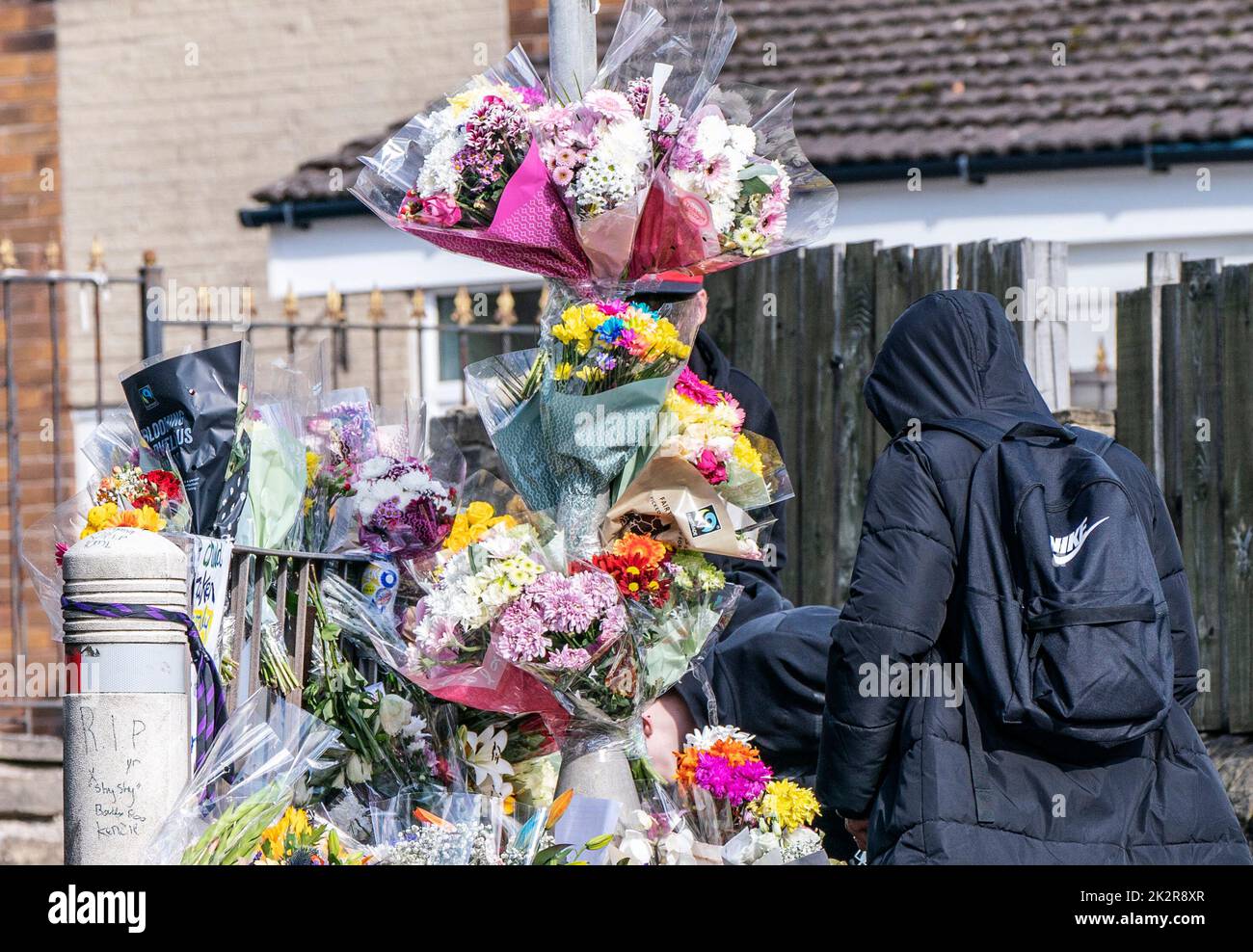 Un alumno ve homenajes florales en la escena de Woodhouse Hill, Huddersfield, donde Khayri McLean, de 15 años, fue apuñalado fatalmente fuera de las puertas de su escuela. Fecha de la foto: Viernes 23 de septiembre de 2022. Foto de stock