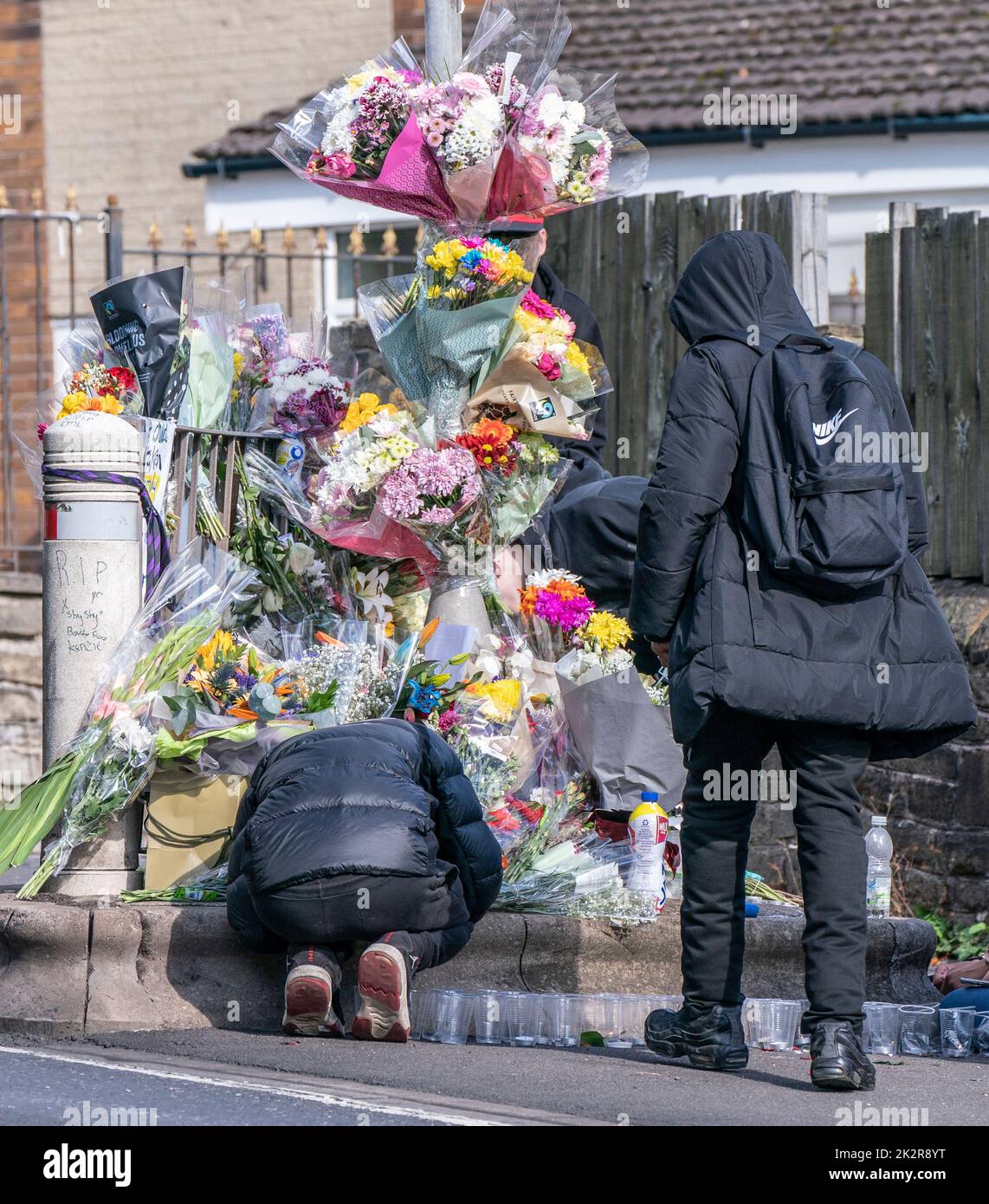 Los alumnos ven tributos florales en la escena en Woodhouse Hill, Huddersfield, donde Khayri McLean, un colegial de 15 años, fue apuñalado fatalmente fuera de las puertas de su escuela. Fecha de la foto: Viernes 23 de septiembre de 2022. Foto de stock