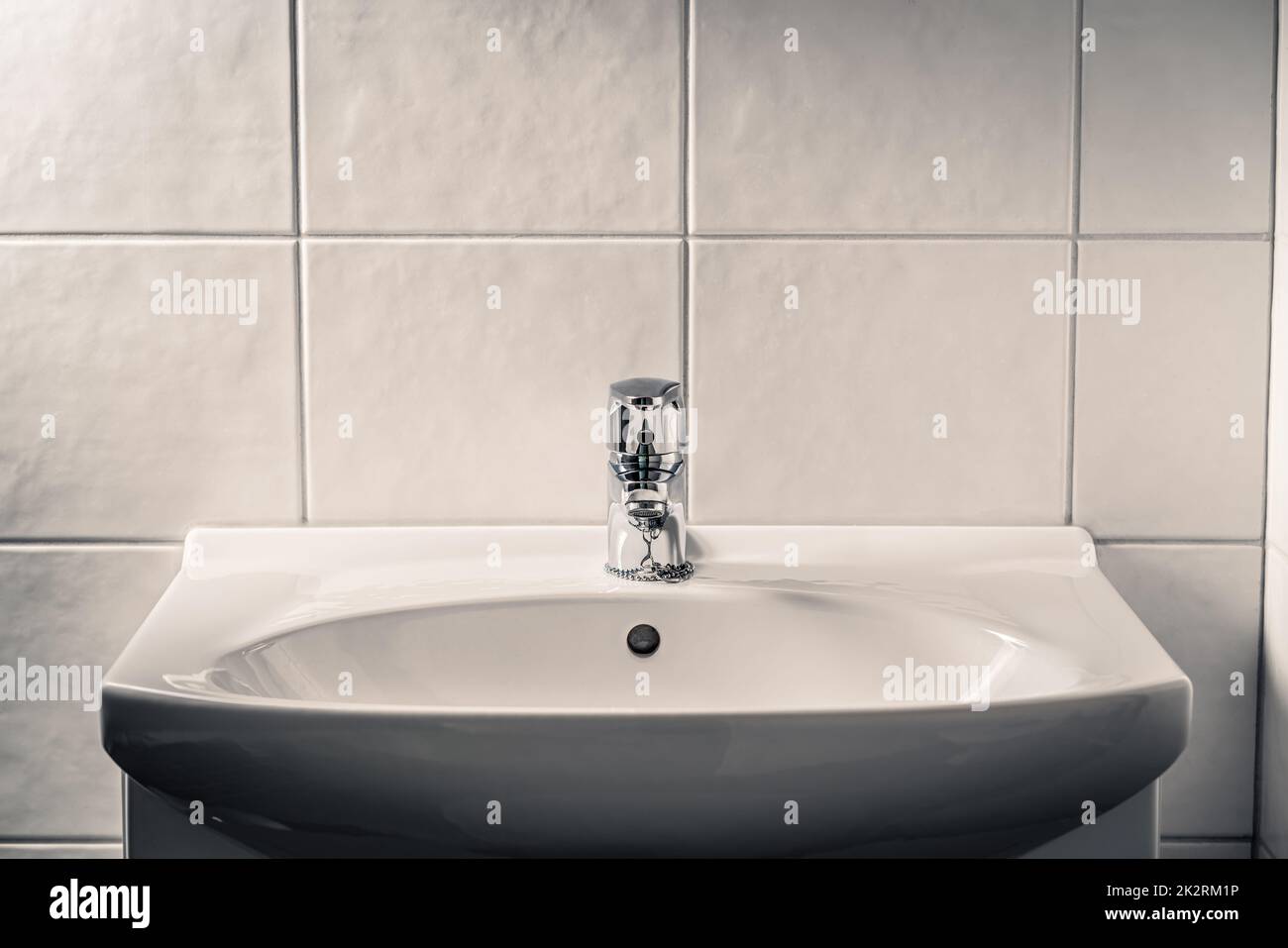 Lavabo del inodoro. Grifo de baño, grifo de agua y lavabo. Luz ambiental dramática con sombras oscuras. Baños públicos. Grunge rústico o viejo lavabo sucio. Foto de stock