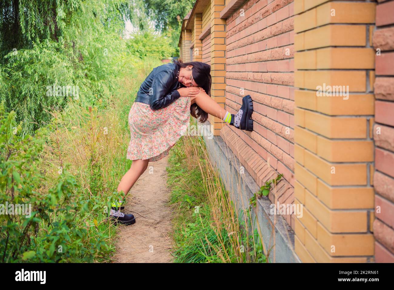 Una joven puso su pie sobre una valla de ladrillo en el parque Foto de stock