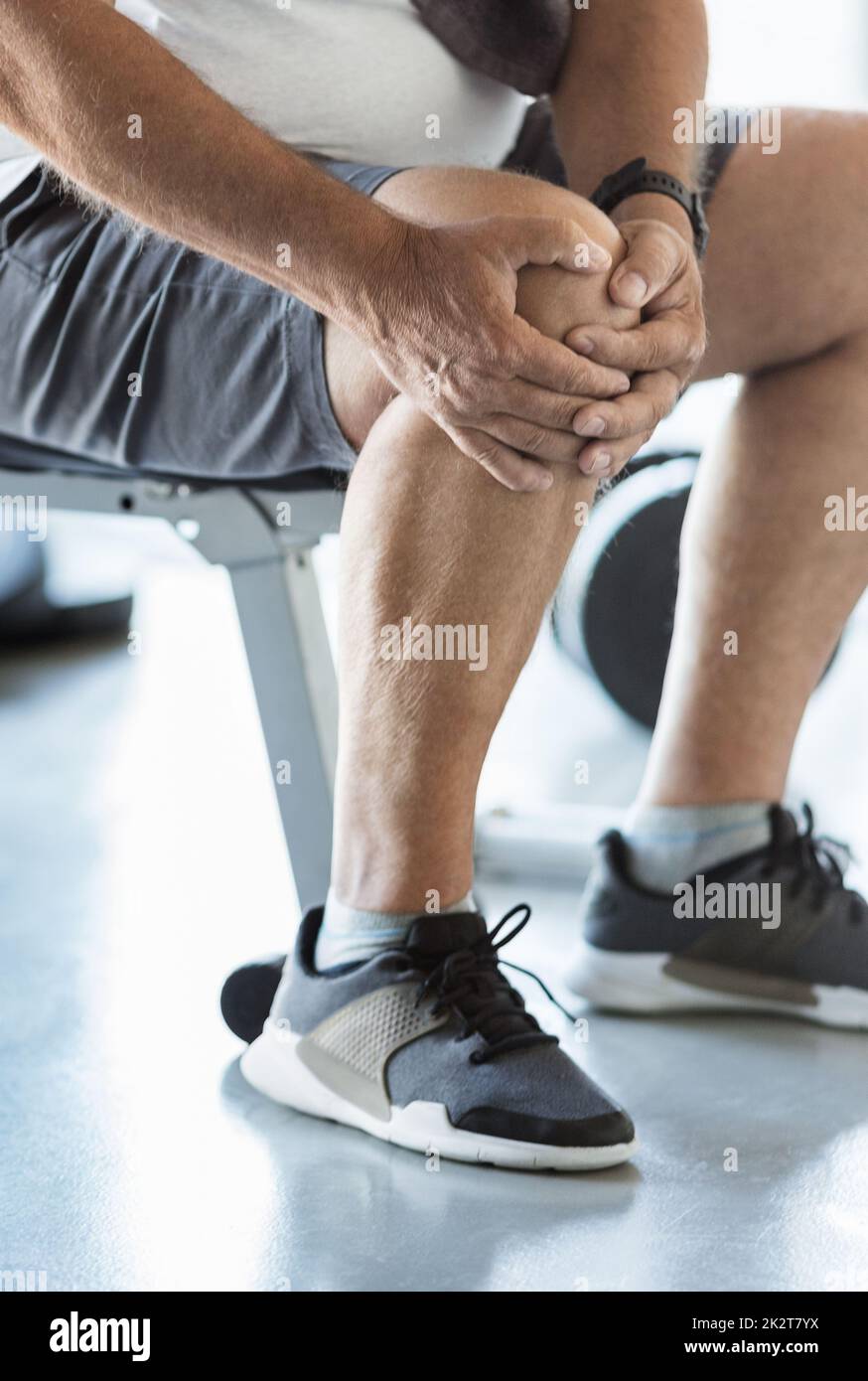 Hombre mayor activo en el gimnasio con lesión en la rodilla Foto de stock
