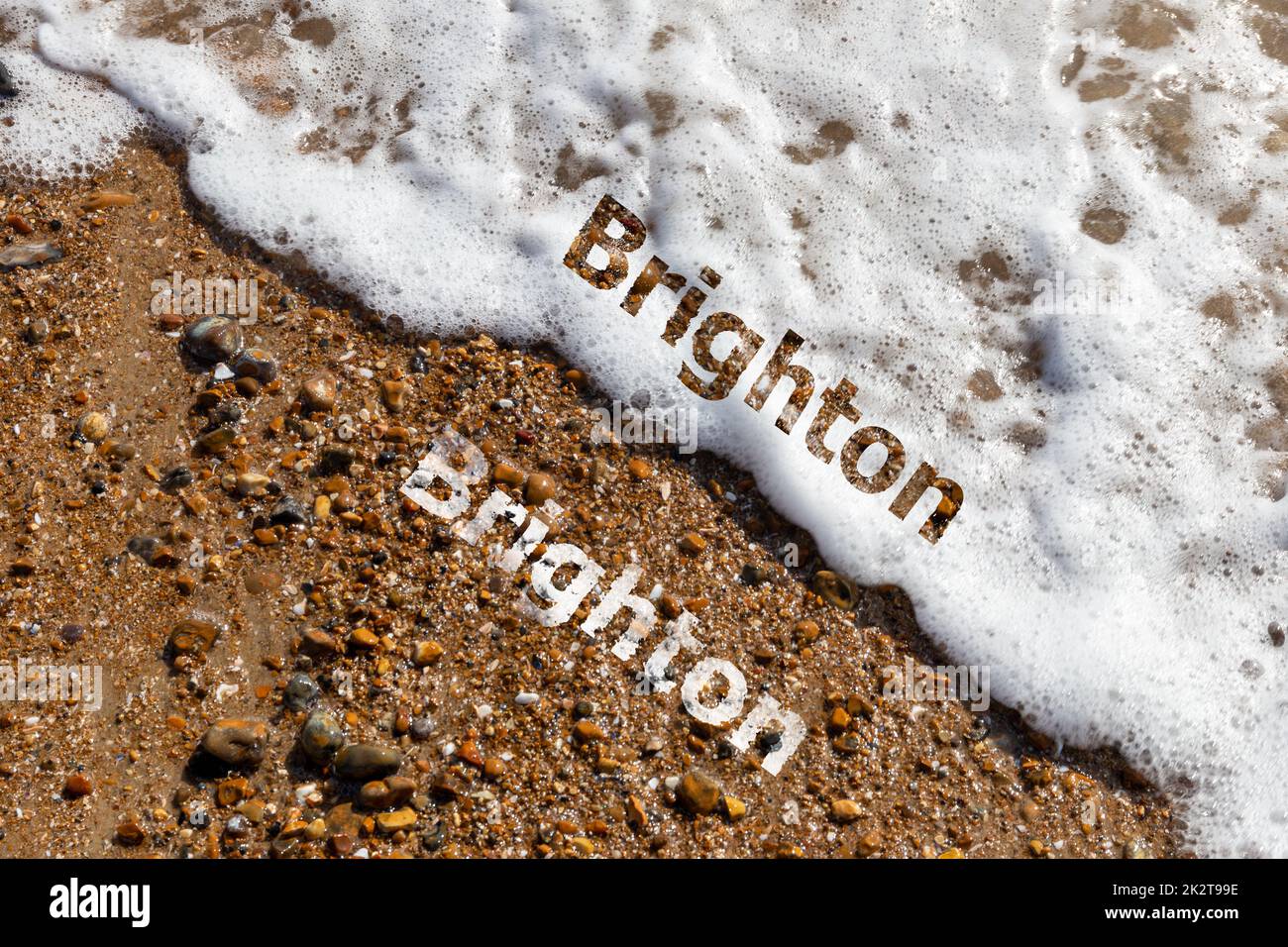 Texto de Brighton cortado en la playa de guijarros y olas rompiendo Foto de stock