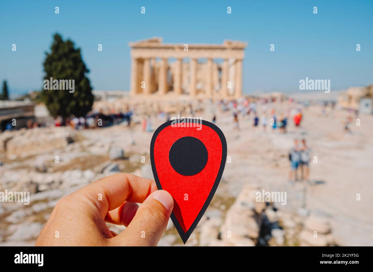 Un hombre sostiene un marcador rojo que señala los restos del famoso Partenón, en la Acrópolis de Atenas, Grecia, lleno de turistas Foto de stock