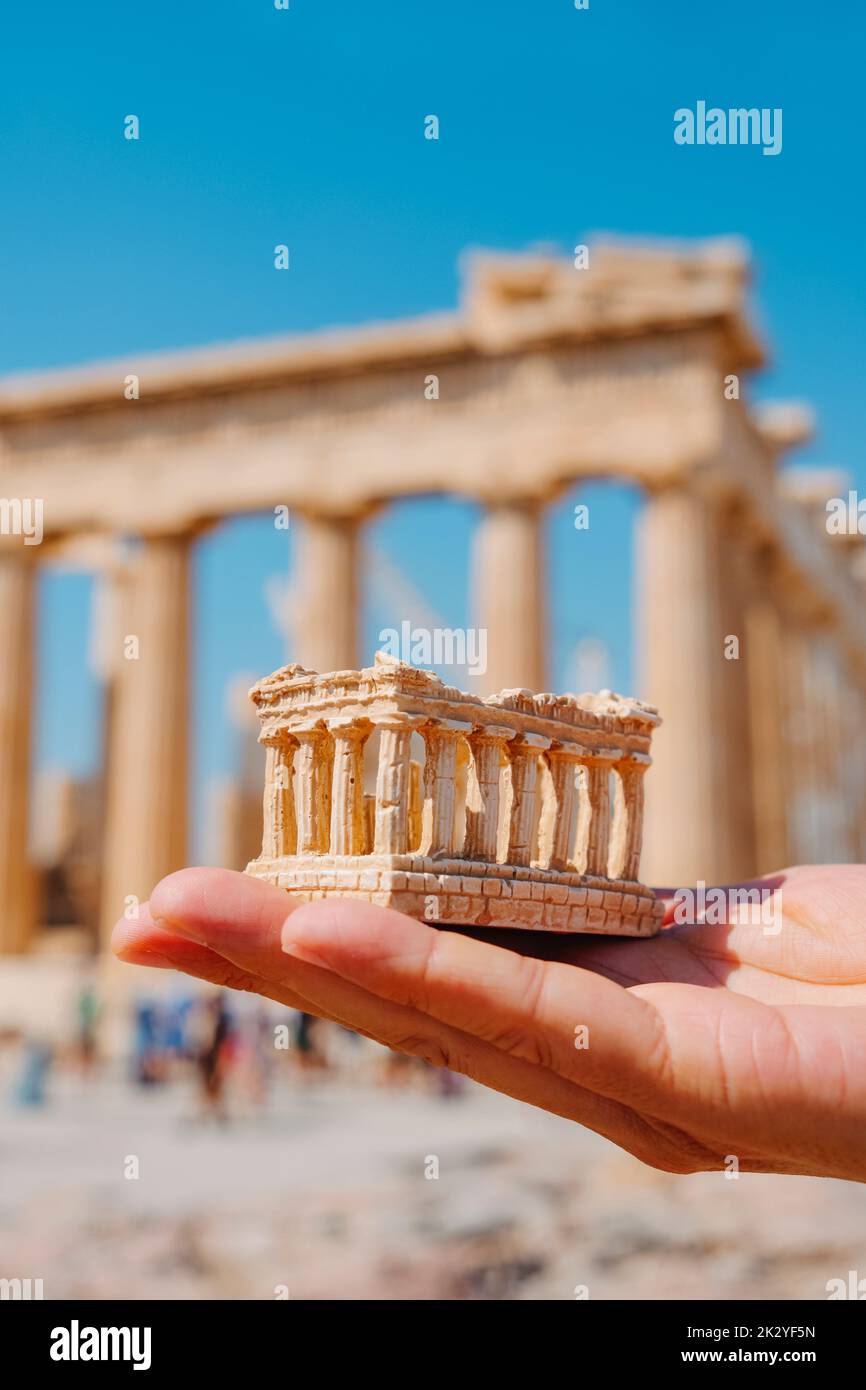 Un hombre sostiene una réplica de los restos del Partenón frente al famoso edificio, en la Acrópolis de Atenas, Grecia Foto de stock