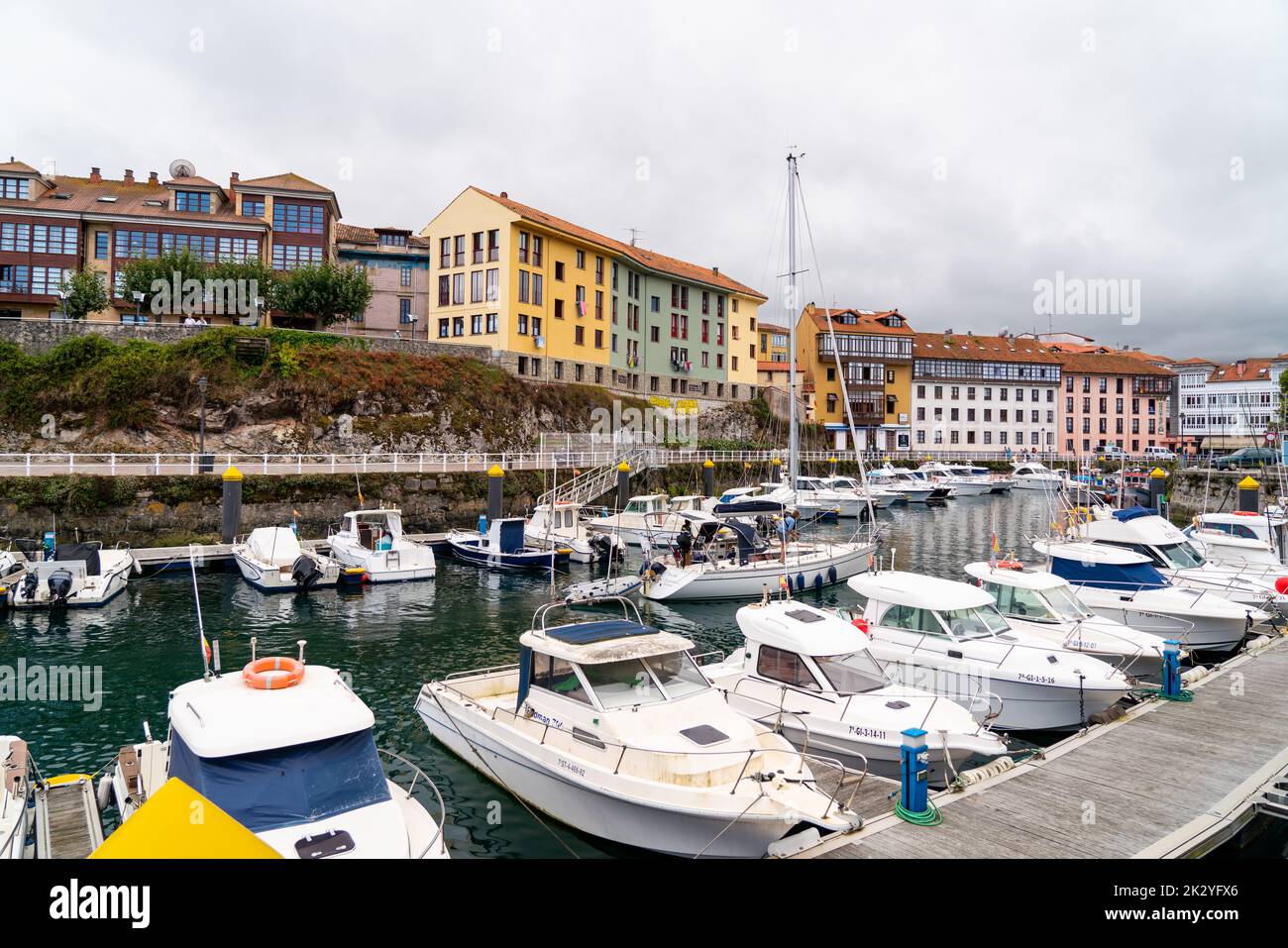 Precioso puerto deportivo de la ciudad de Llanes, en el norte de España -  Asturias. Vista de los barcos atracados. En el fondo la ciudad de Llanes  con edificio de colores y