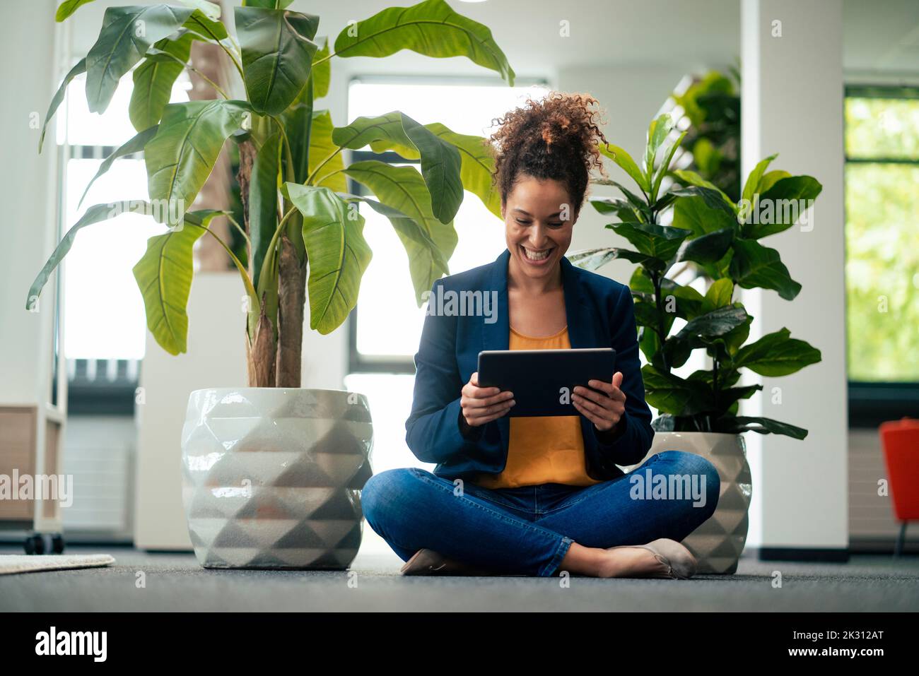 Alegre mujer de negocios con un tablet PC sentado en la oficina Foto de stock