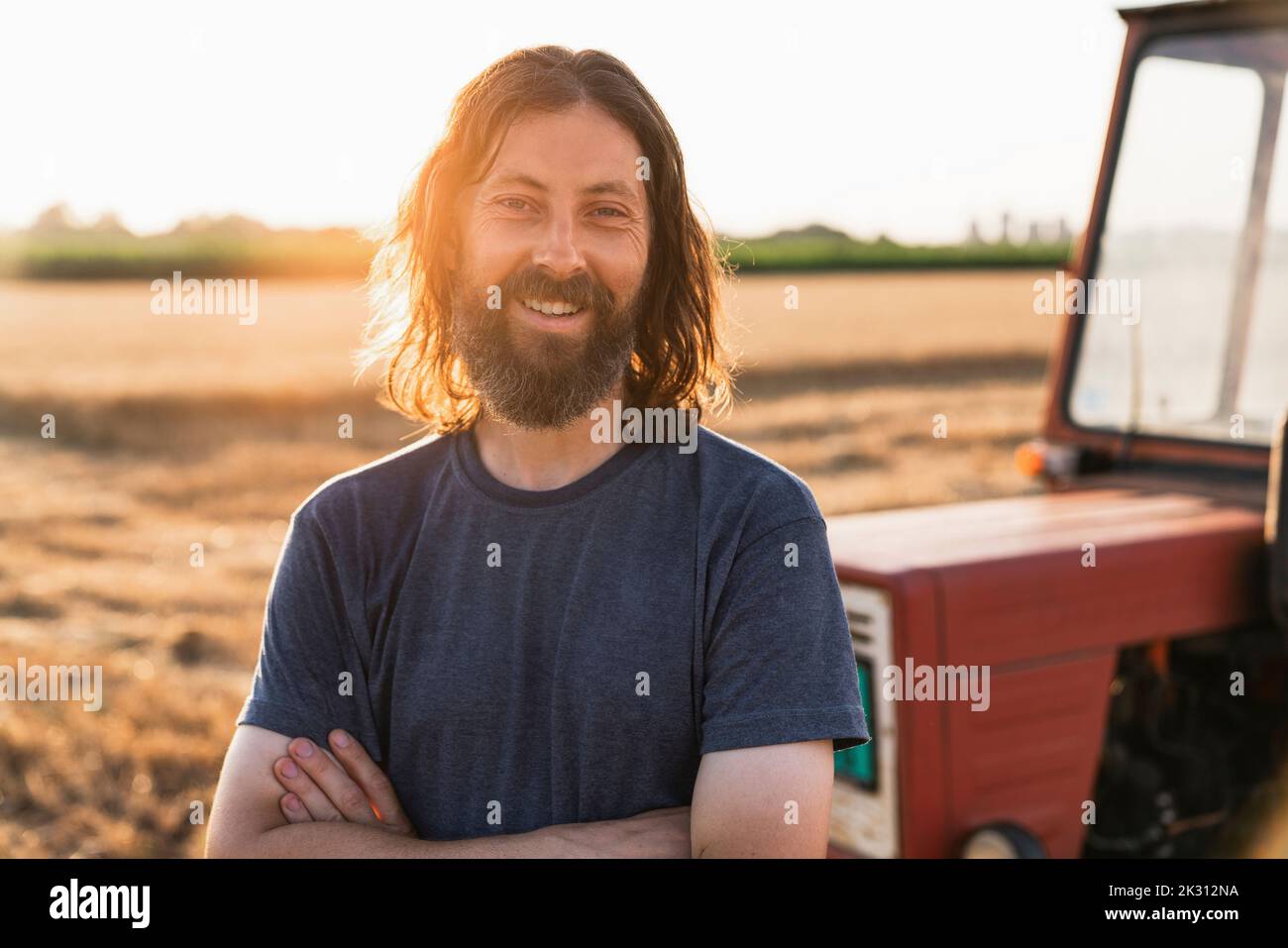 Sonriendo granjero barbudo con los brazos cruzados Foto de stock