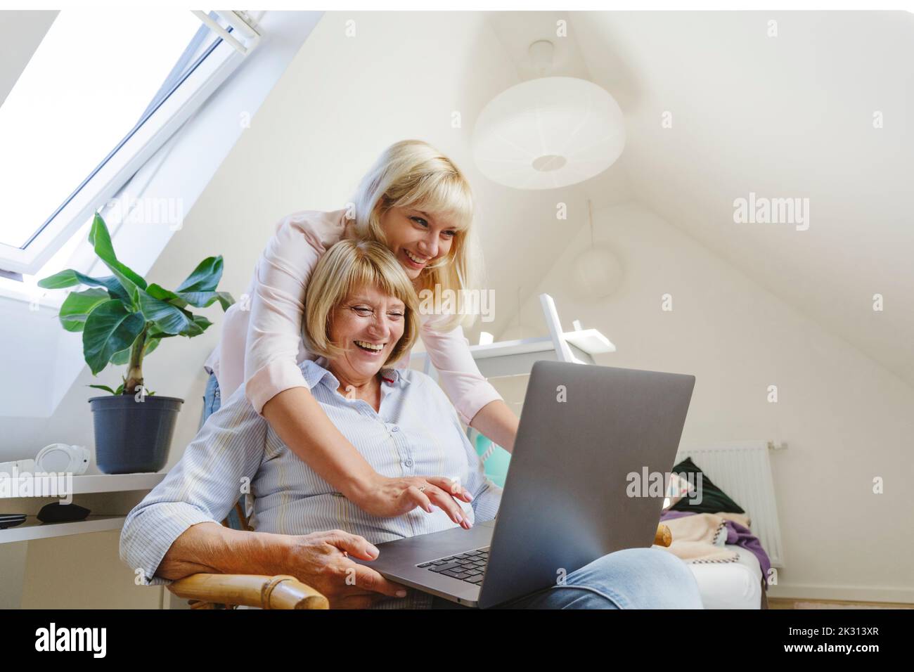 Mujer rubia feliz con madre usando el portátil en casa Foto de stock