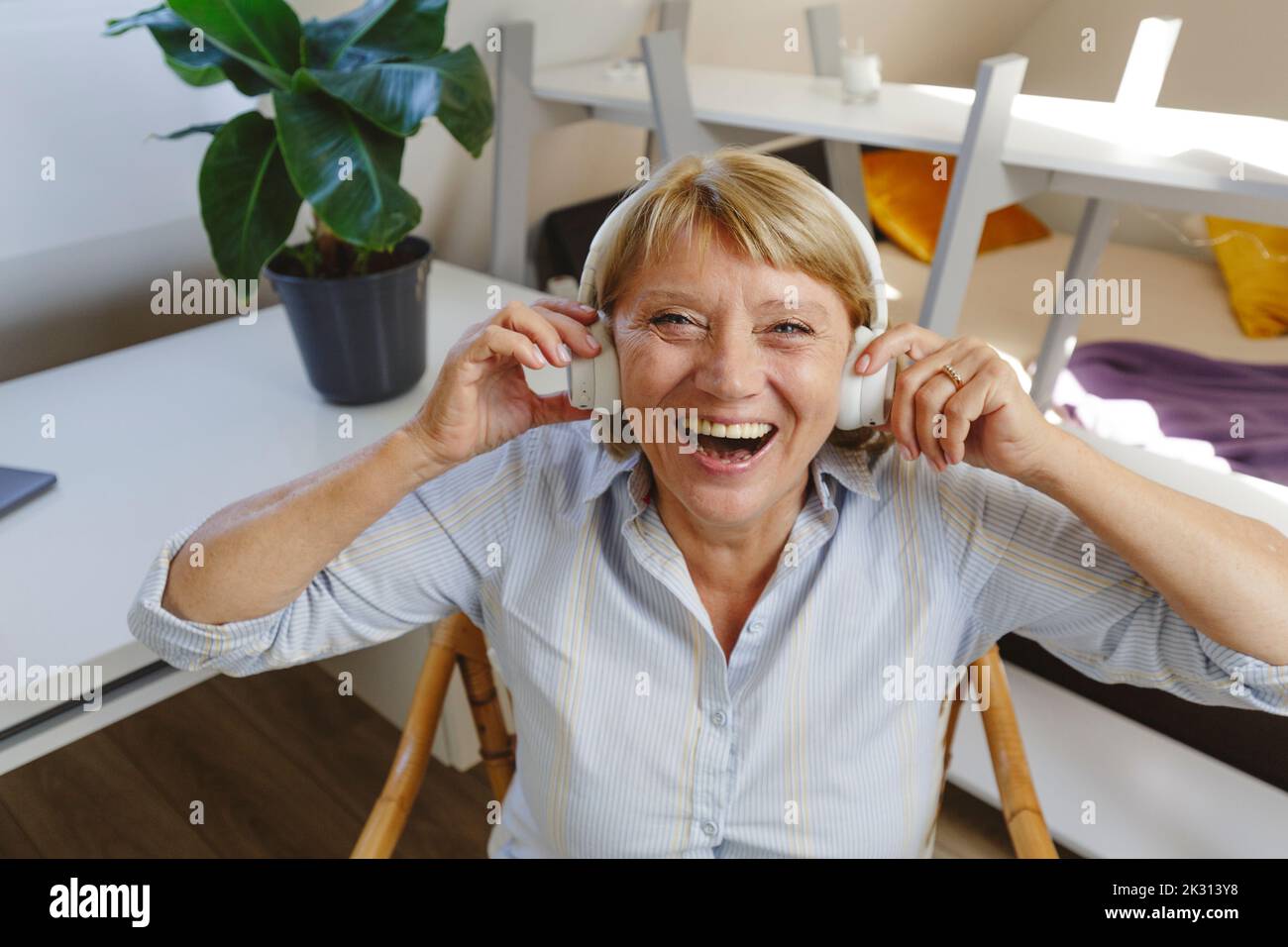 Alegre mujer mayor escuchando música a través de los auriculares inalámbricos Foto de stock