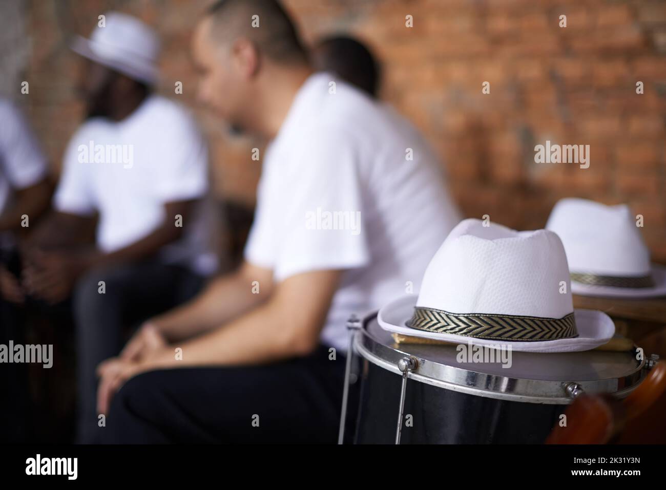Sienta el ritmo del carnaval, un sombrero en un tambor con los miembros de la banda sentados en el fondo. Foto de stock