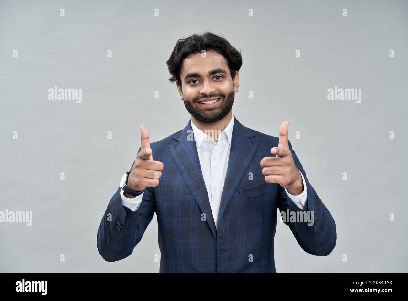 Sonriente hombre de negocios árabe indio señalando a usted aislado en beige. Foto de stock