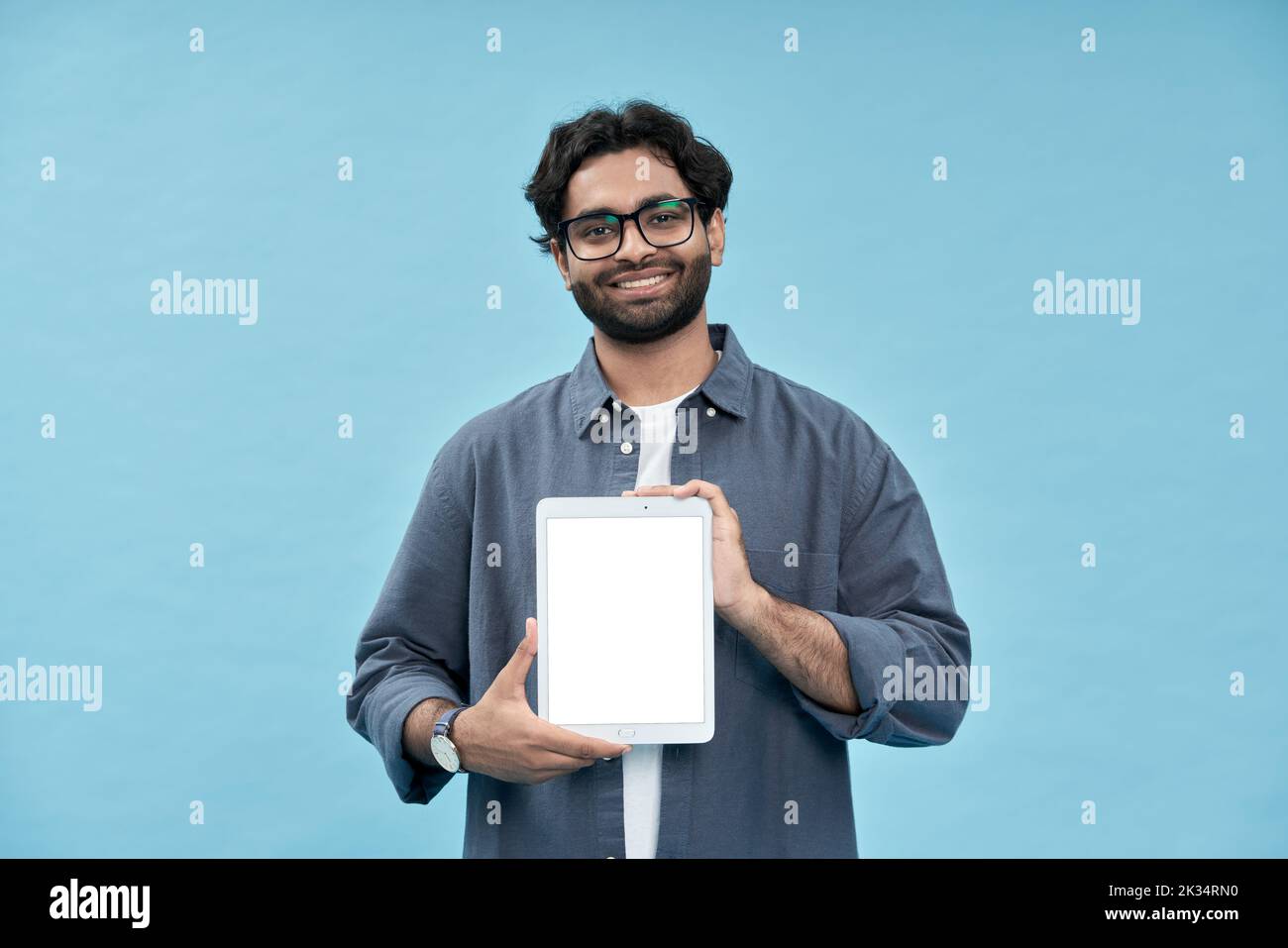 Sonriente estudiante árabe mostrando la pantalla de maqueta de la tableta digital presentando el anuncio en línea. Foto de stock