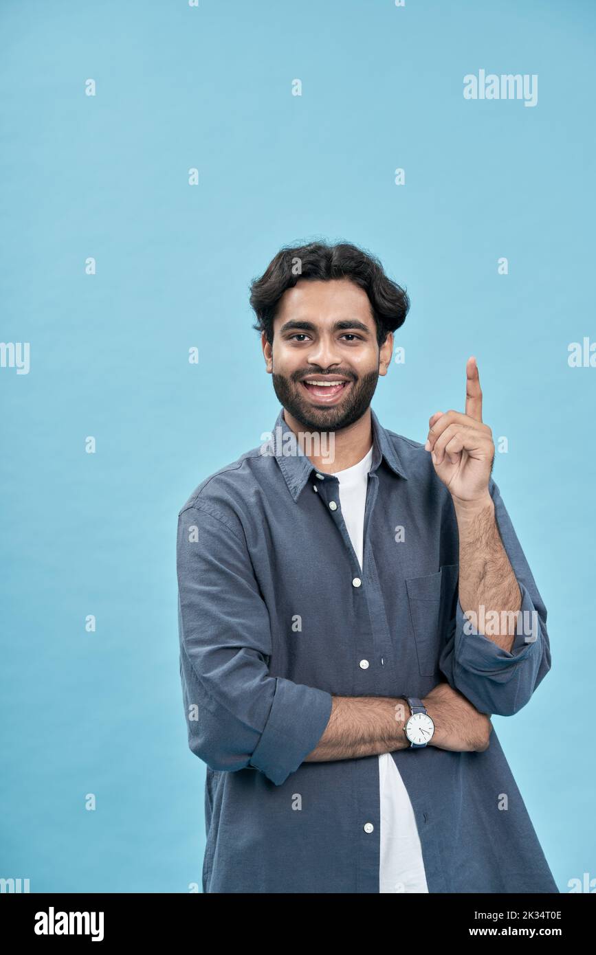 Feliz hombre árabe emocionado señalando dedo nuevo gran idea aislado en azul. Foto de stock
