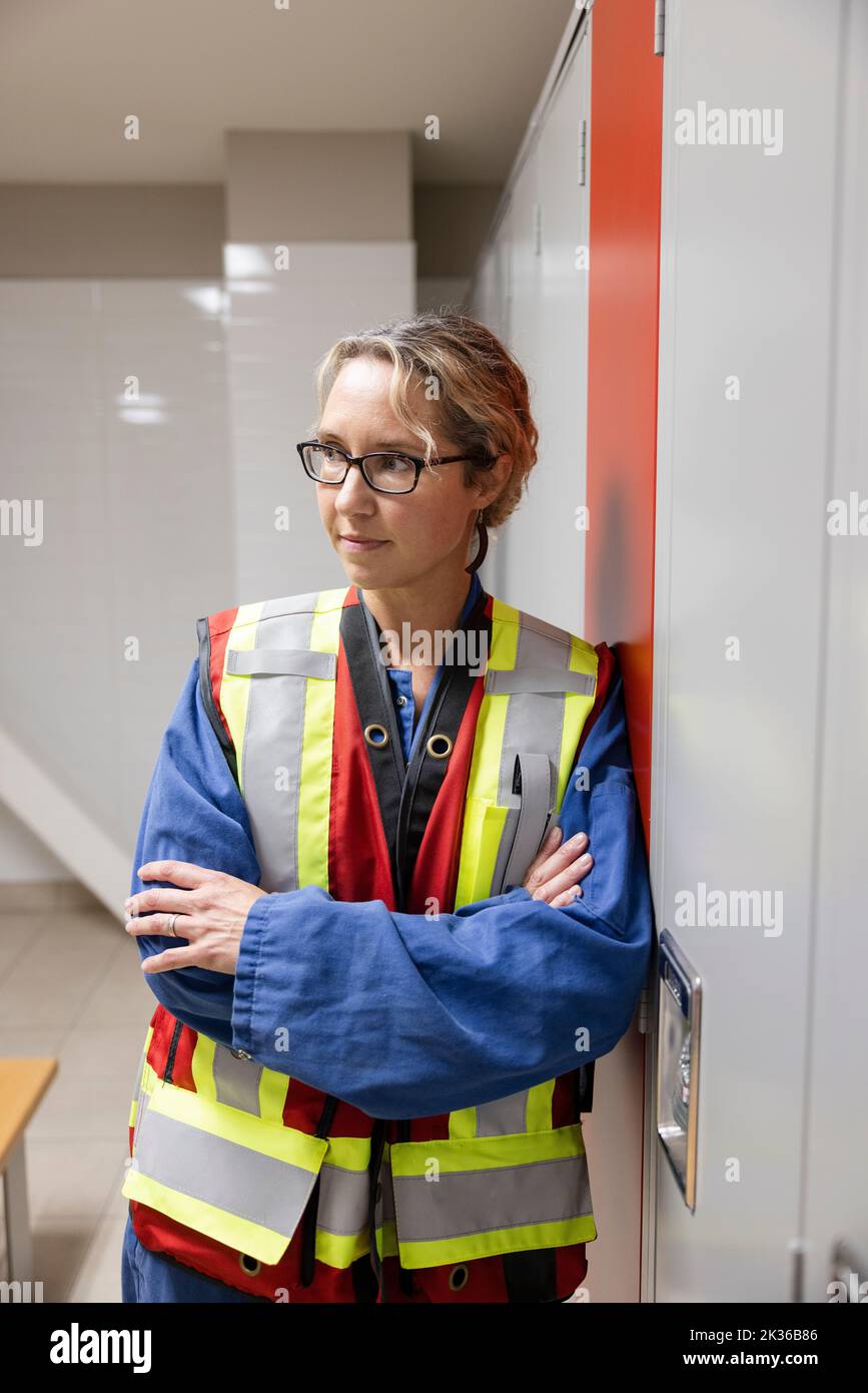 Trabajadora en chaleco reflectante en el vestuario Foto de stock