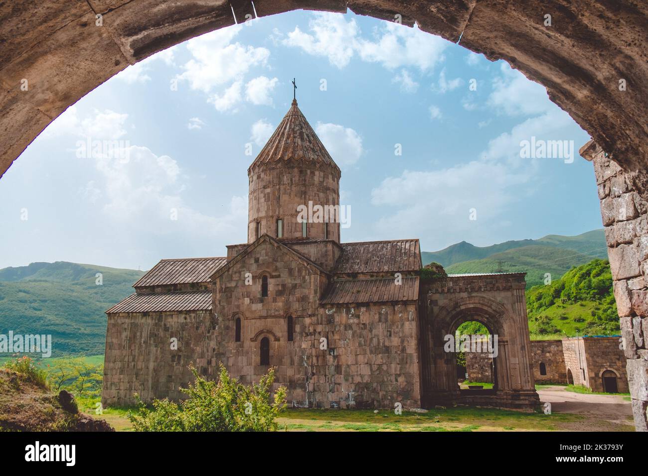 Tatev antiguo monasterio vista baja desde el arco. Armenia mejor famosa ubicación de viaje. Destino turístico popular. Antigua arquitectura de la iglesia medieval. Colinas verdes de montaña en el fondo. Viajes, turismo Foto de stock