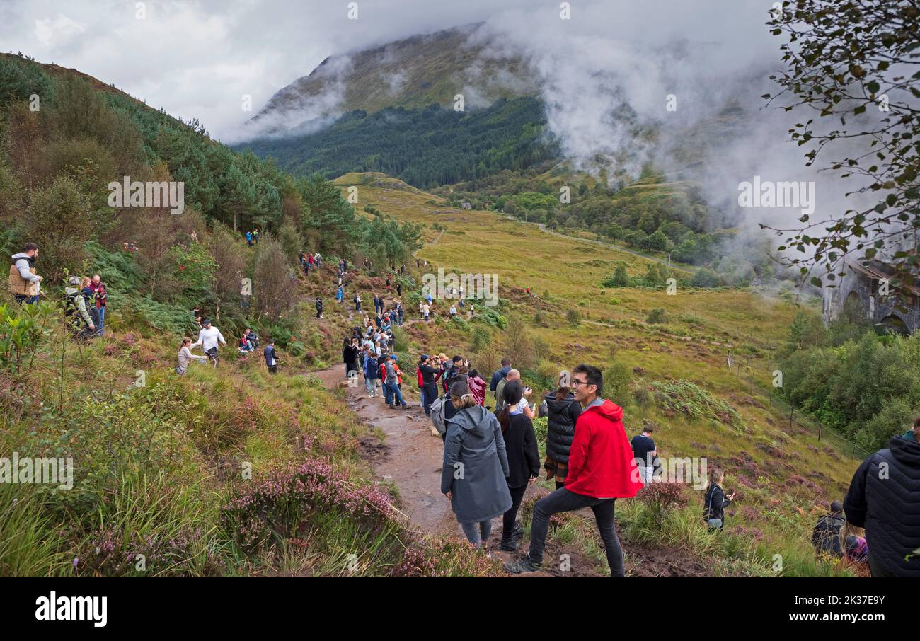 Los turistas salen de la colina después de ver el tren de vapor jacobita Glenifinnan, Lochaber, Scottish Highlands, Escocia, Reino Unido Foto de stock