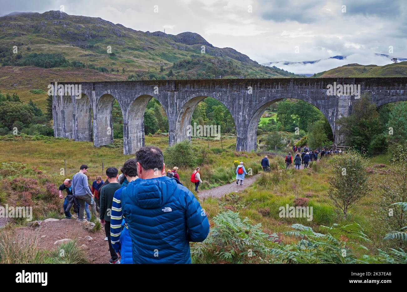 Los turistas salen de la colina sobre el viaducto de Glenifinnan, Lochaber, Scottish Highlands, Escocia, Reino Unido Foto de stock