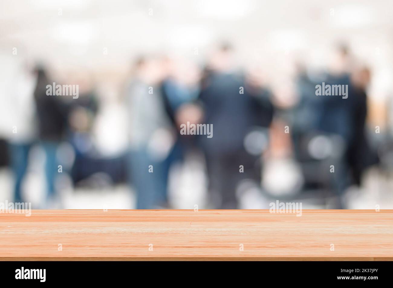 Mesa de madera vacía sobre la luz suave borrosa gente de negocios reunión en el interior de la oficina con espacio para la exhibición del producto en los medios de comunicación en línea anunciar Foto de stock