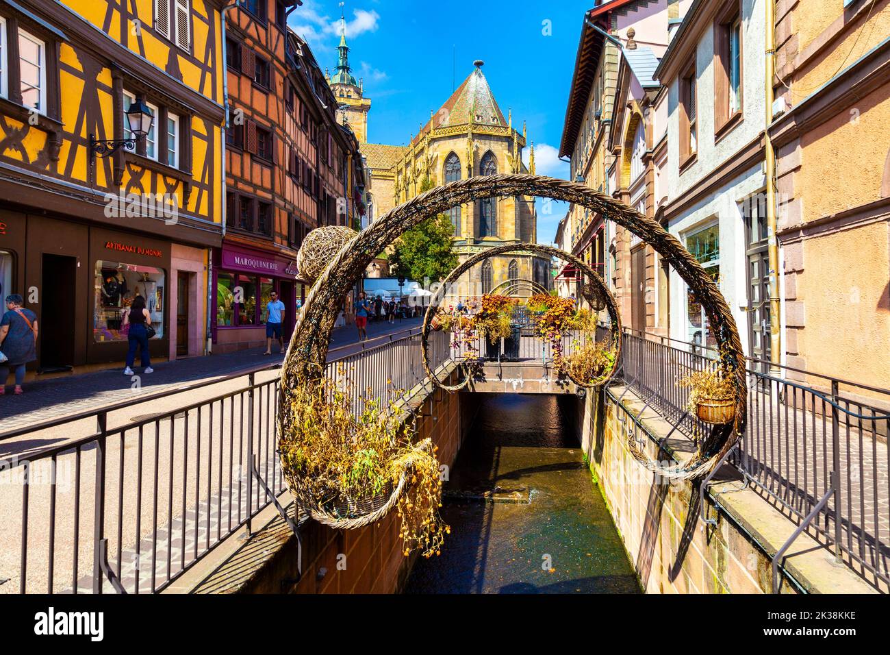 Canal decorado con arcos a lo largo de la Rue de l'Église con la Iglesia de San Martín al fondo, Colmar, Alsacia, Francia Foto de stock