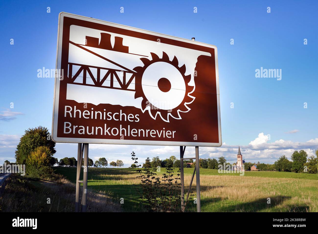 Firme con una simbólica excavadora de ruedas junto a la autopista A44 cerca de Hasselweiler en Renania del Norte-Westfalia, Alemania. El llamado 'comité de información turística' señala la atracción industrial-cultural de la zona minera de lignito renano, en la que el lignito se extrae en minas a cielo abierto en enormes pozos. Foto de stock