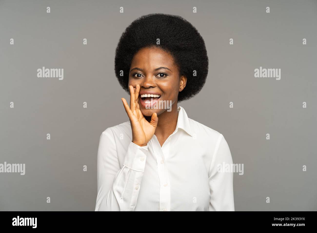 Mujer afroamericana contando historias divertidas realiza boceto en la audición contra el estudio gris Foto de stock