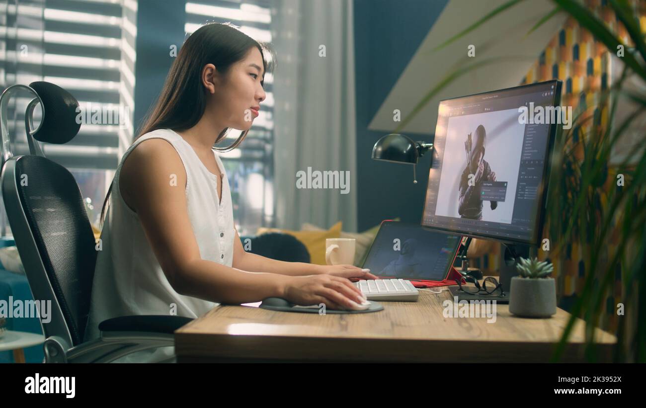 Mujer asiática creando 3D modelo de videojuego personaje en el programa profesional con ordenador y tableta digital mientras trabaja en la oficina doméstica Foto de stock