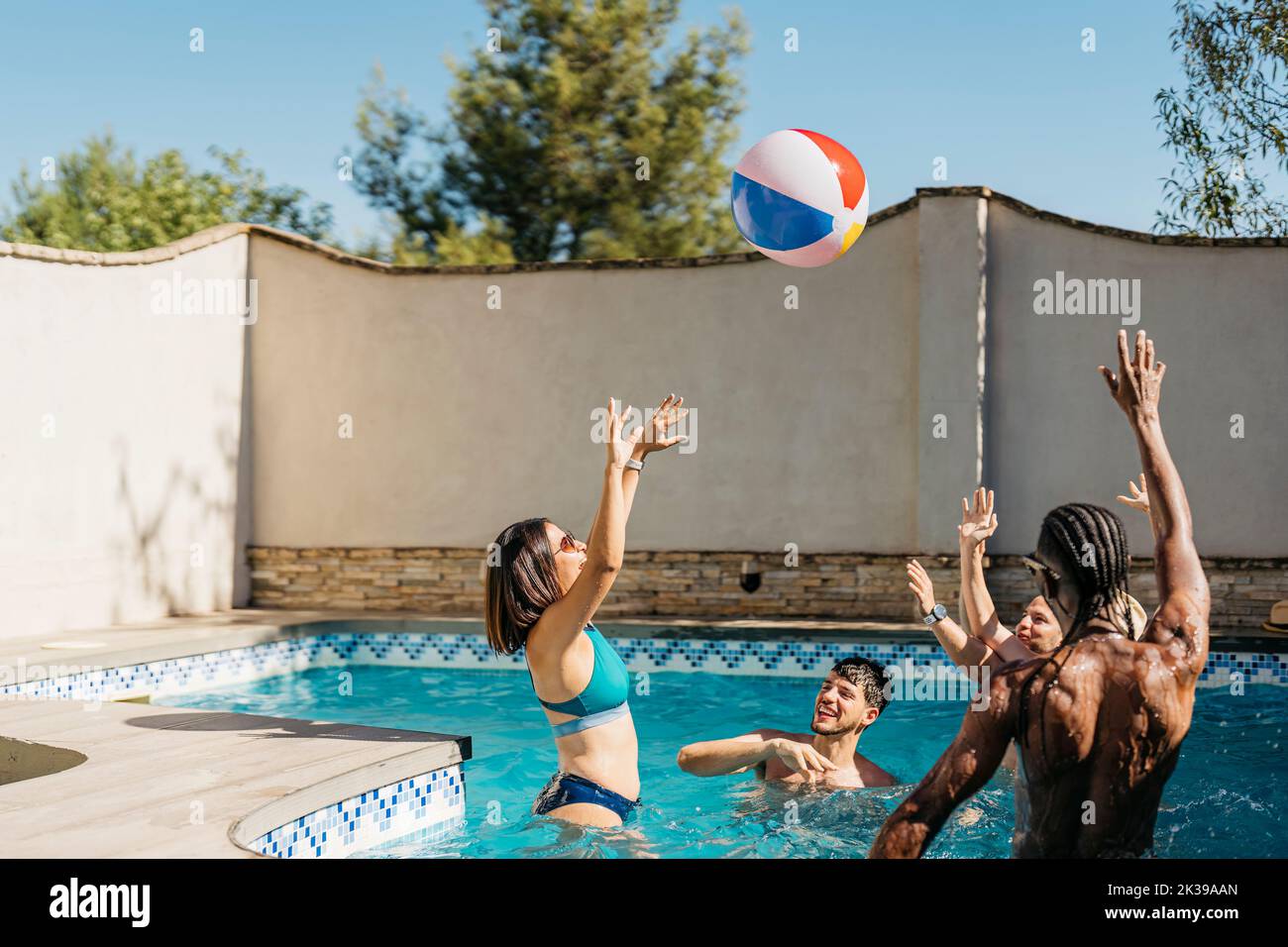 grupo multiétnico jugando en una piscina con una pelota Foto de stock