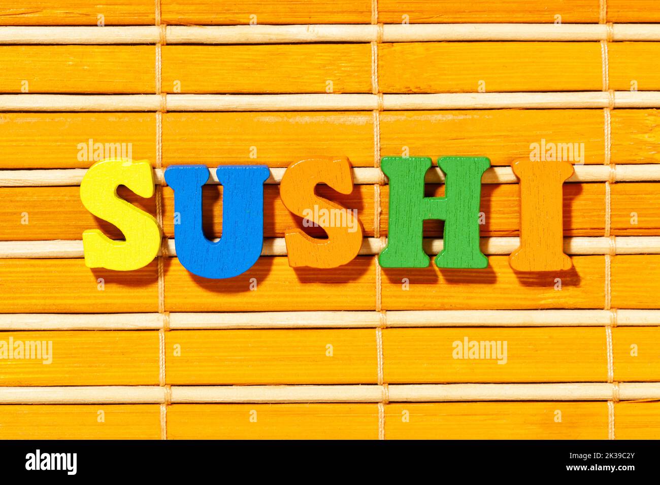 Palabra sushi - Inscripción con letras de colores en la estera de bambú Foto de stock