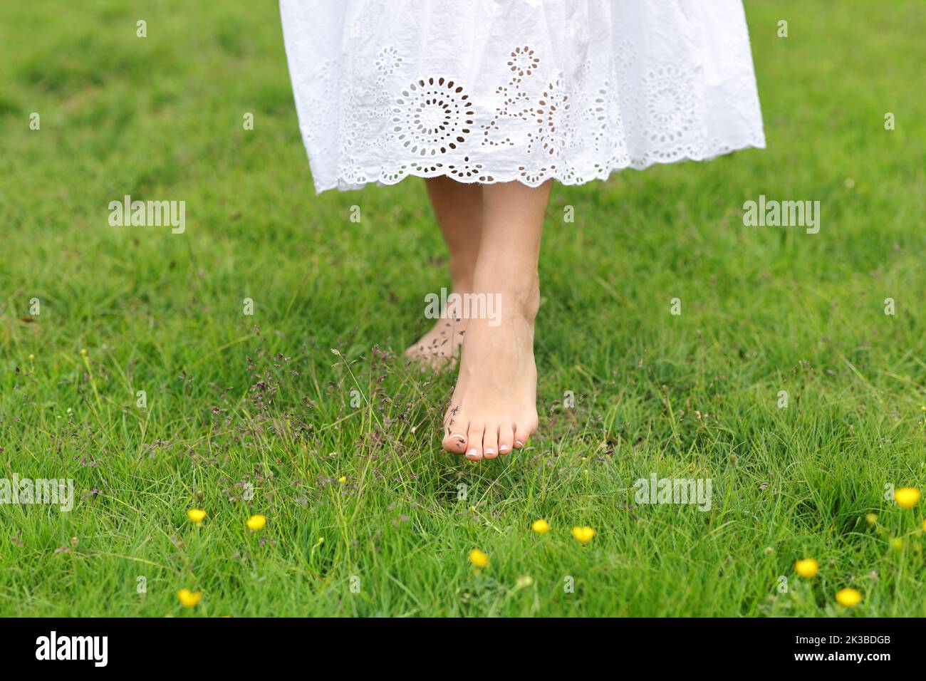 Vista frontal retrato de una mujer con los pies descalzos caminando sobre la hierba Foto de stock