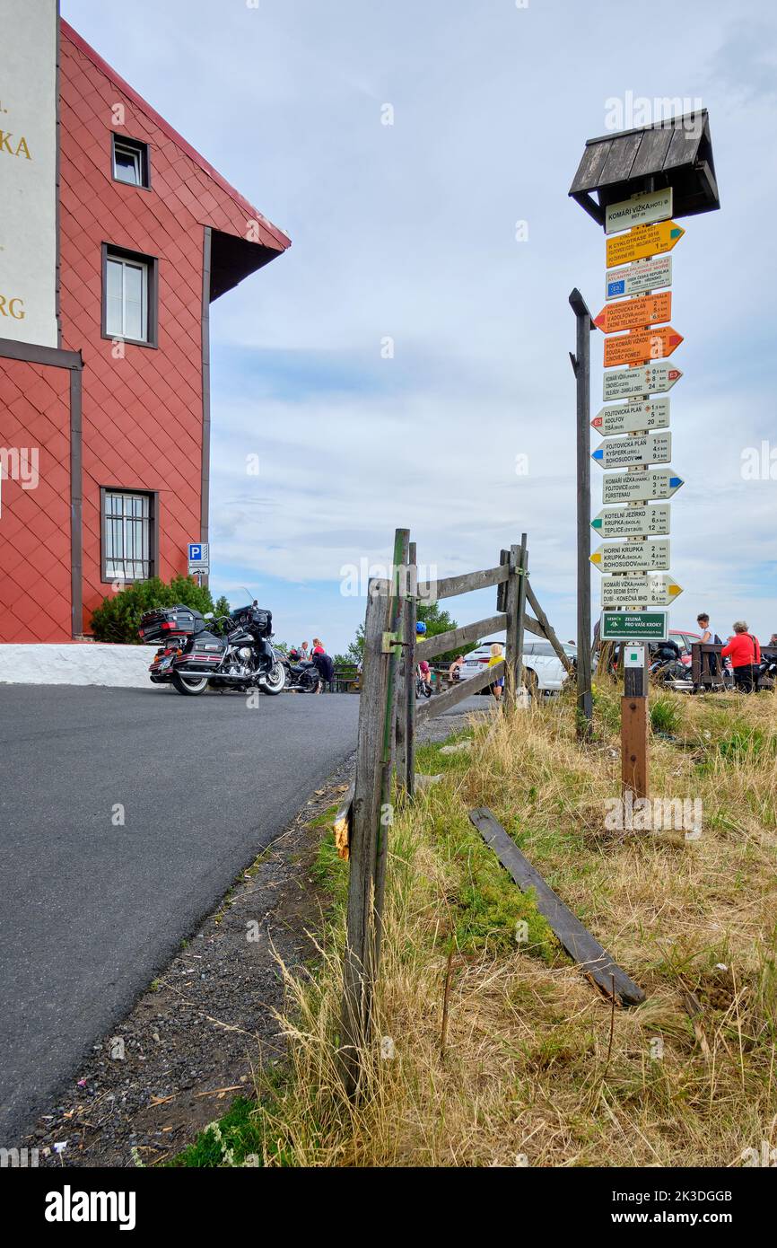 En un poste delante de la torre vizka de Komari, en la colina de Komari hurka, república Checa, hay numerosas señales de dirección. Foto de stock