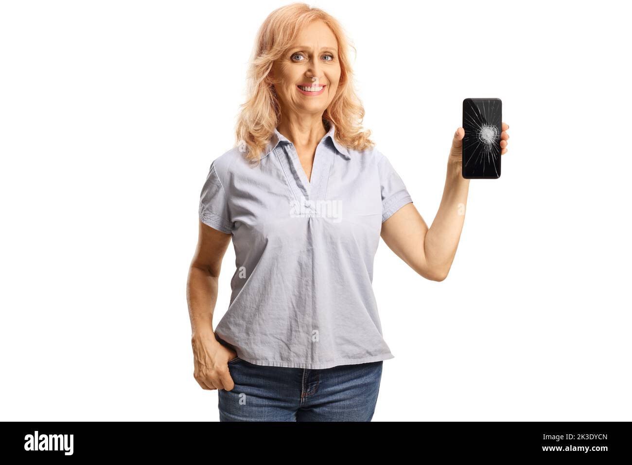Mujer madura informal mostrando un smartphone con una pantalla rota aislada sobre fondo blanco Foto de stock