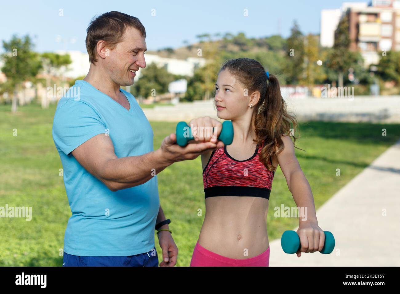 Chica con padre haciendo ejercicio con mancuernas Foto de stock