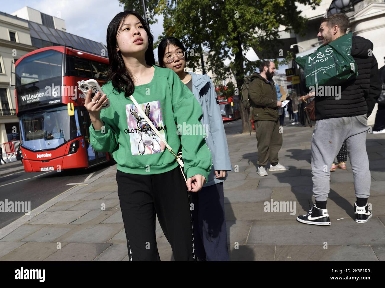 Londres, Inglaterra, Reino Unido. Joven asiática con un teléfono móvil en el Strand Foto de stock